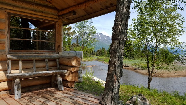 Porch of a log cabin overlooking a creek