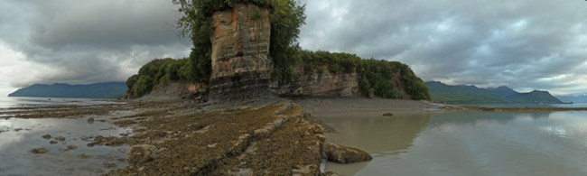photo of a steep, rocky bluff surrounded on three sides by water.