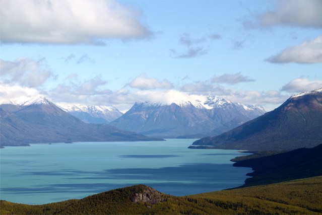 a light blue lake surrounded by steep mountains which are dusted in snow