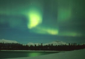 green light over a dark, snowy mountain landscape