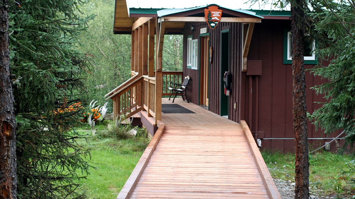 photo of a wooden ramp leading to a wooden building in a forest.