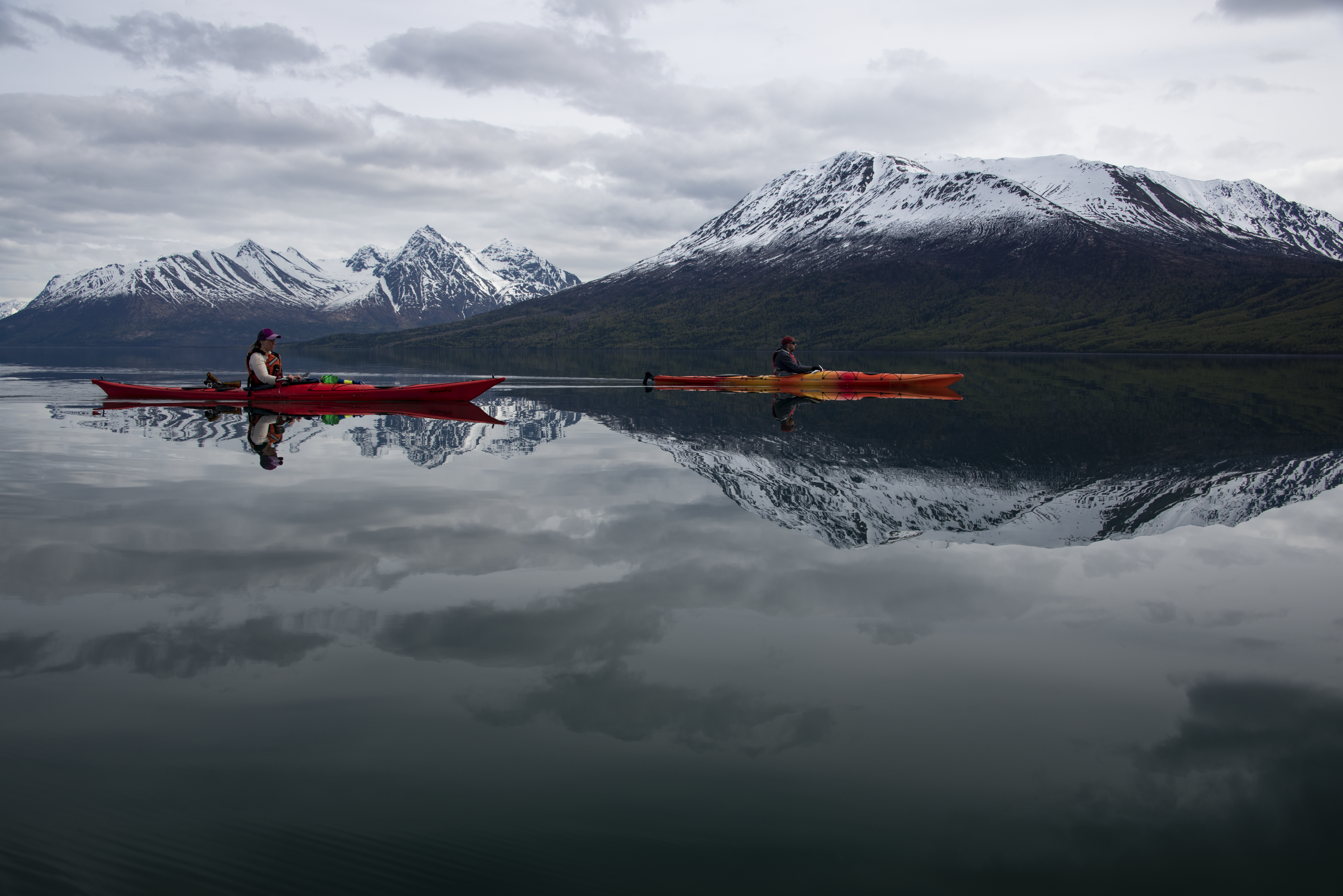Two kayakers paddle on still waters of Lake Clark