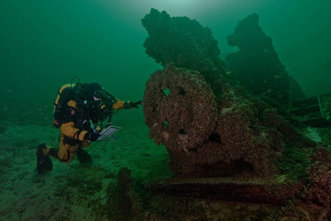 Diver takes note next to underwater gold dredge