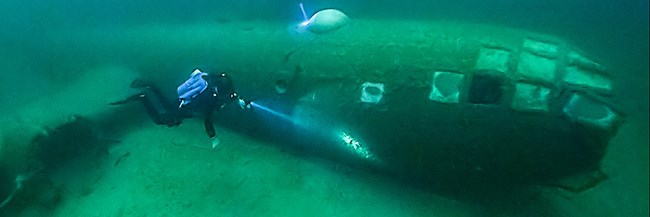 Diver swims next to a submerged item