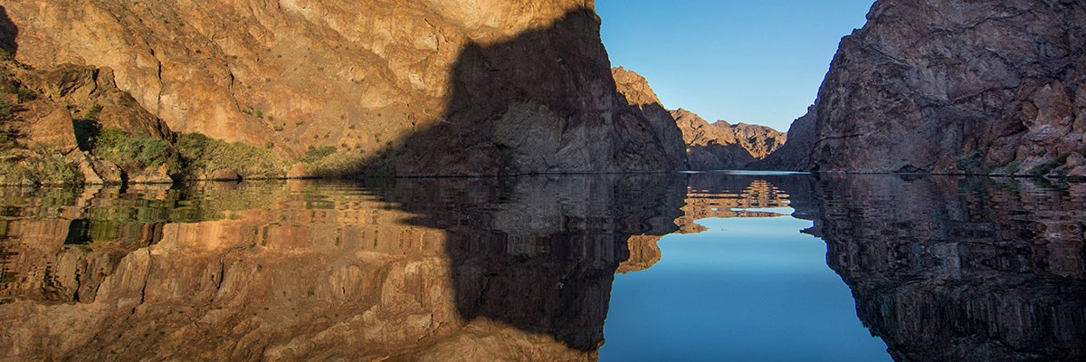 Blue sky showing through cliff walls by a body of water