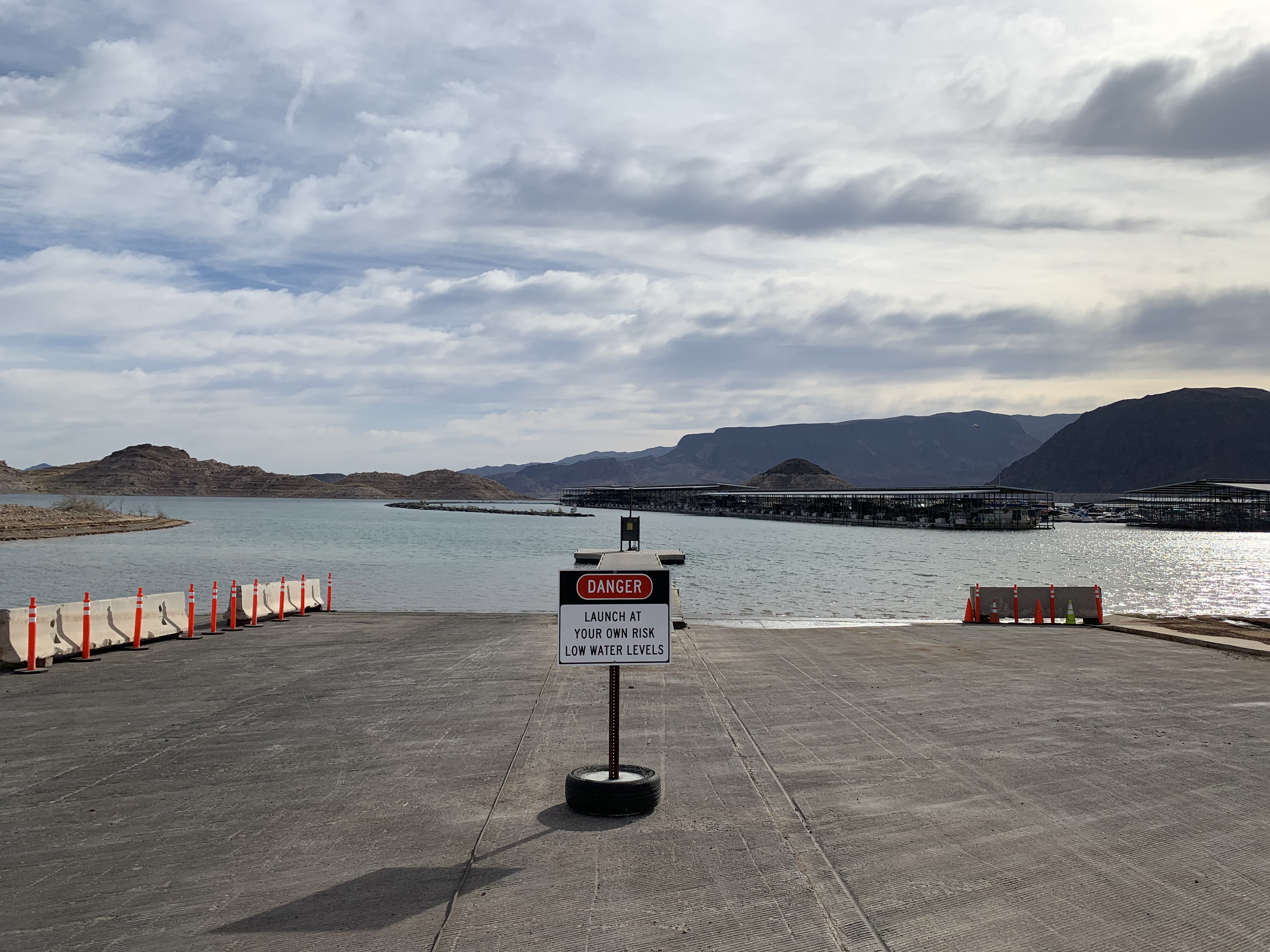 Construction equipment and a sign on a launch ramp saying 'launch at your own risk - low water levels'