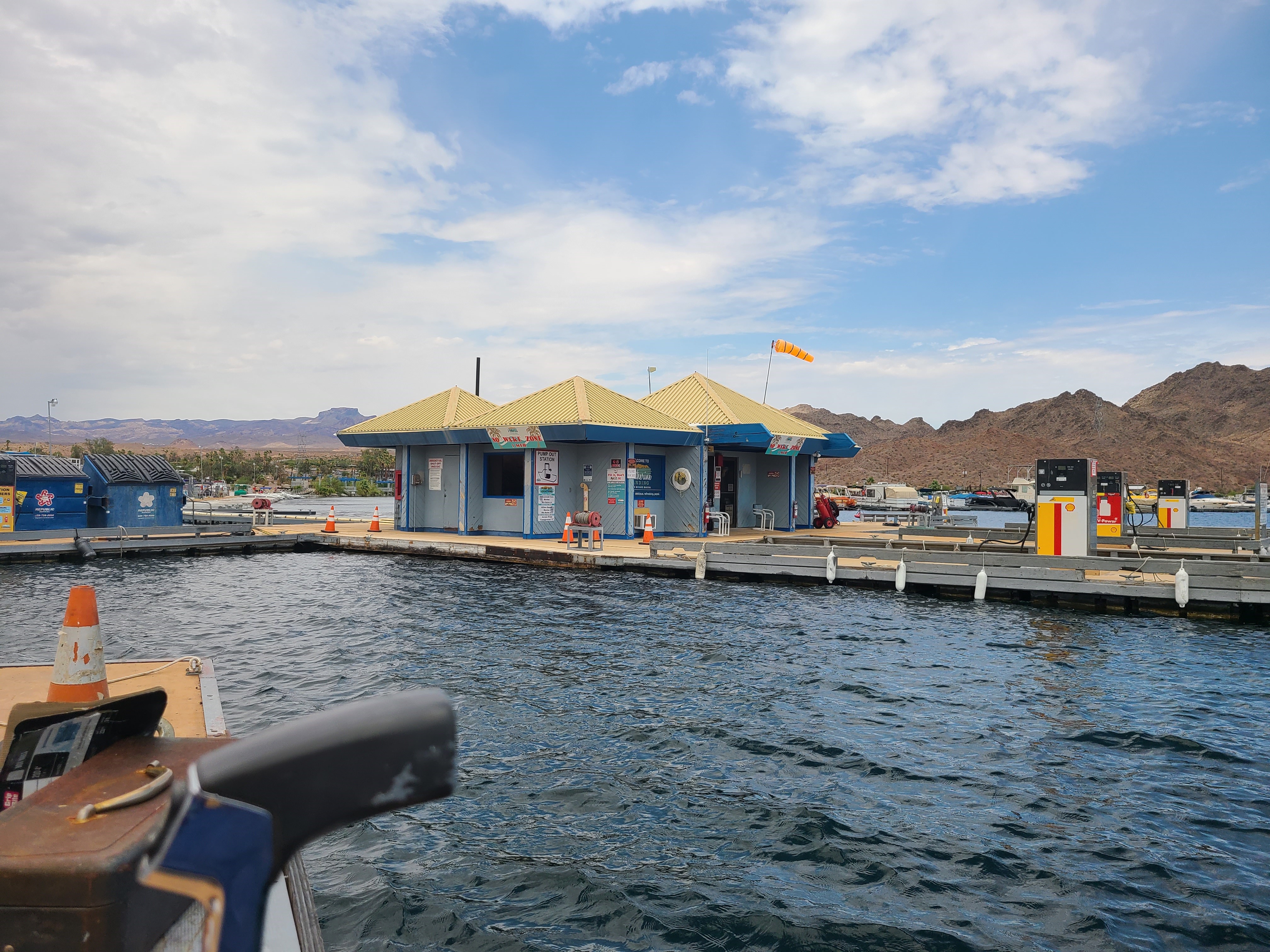 An old boat dock with fuel pumps and a small building on the dock.