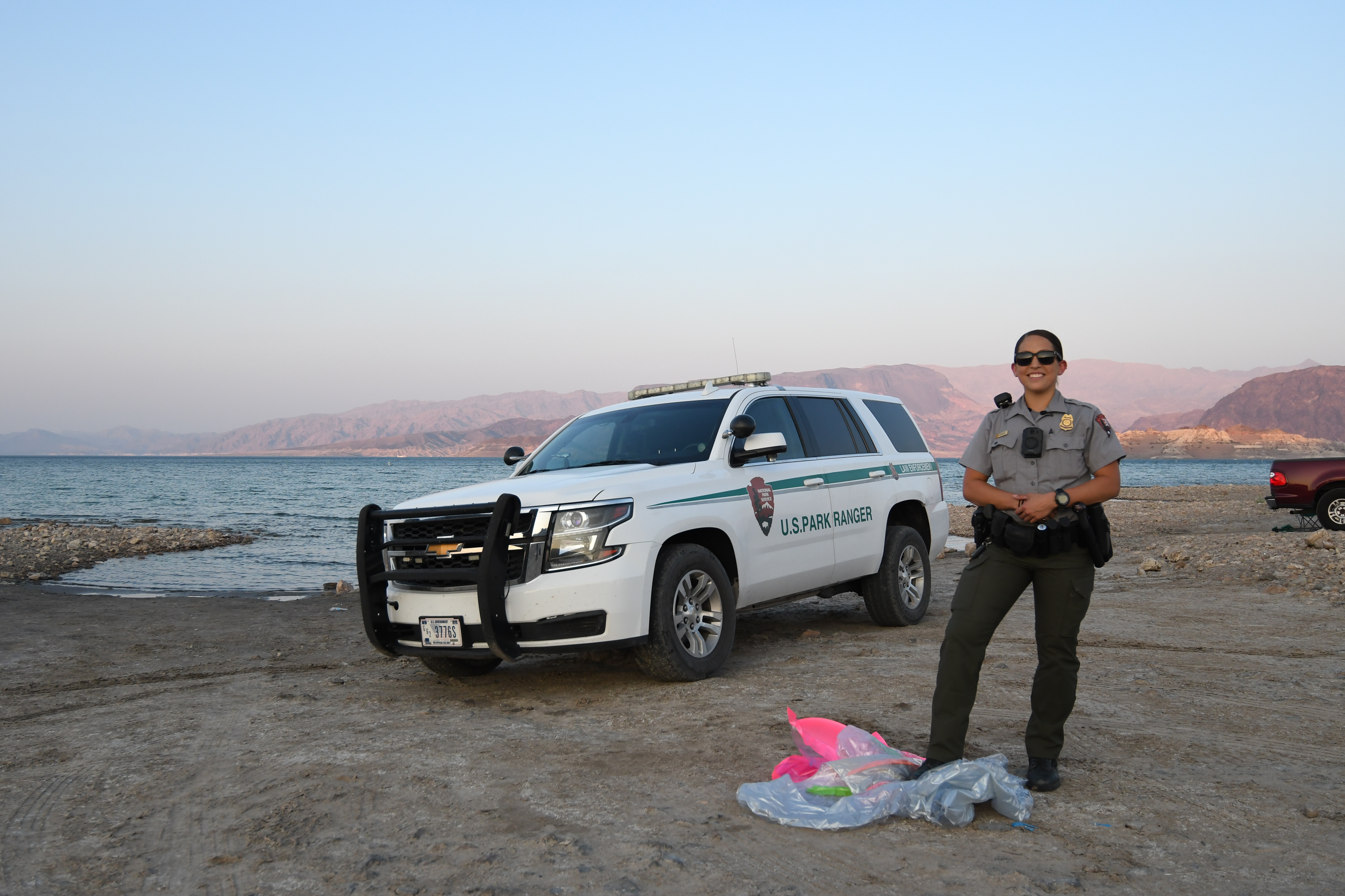 Park ranger with pool float with SUV and lake in background.