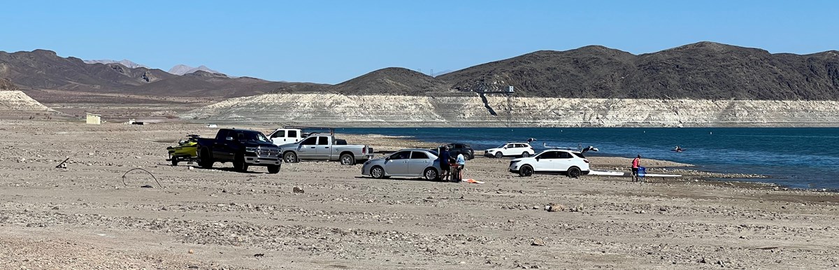 Cars and people along the shoreline at Boulder Beach
