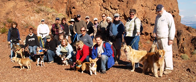 Large group of hikers pose with dogs on trail through red rock walls Large group of hikers pose with dogs on trail through red rock walls