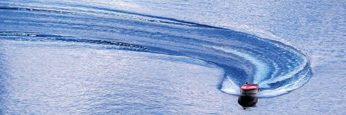 Red powerboat with large curved wake