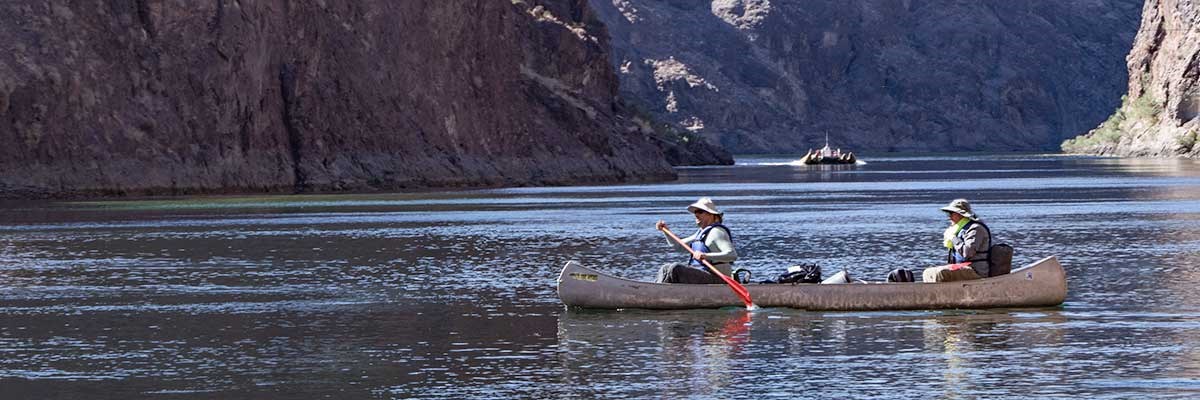 Two people on canoe, large canyon in background