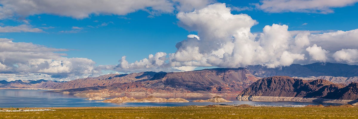 Mountains dotted with red sandstone in body of water, cloudy sky