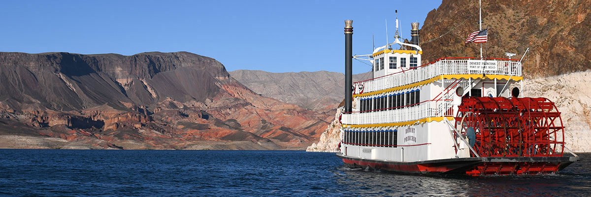 Paddle wheel boat at right headed toward red sandstone hills