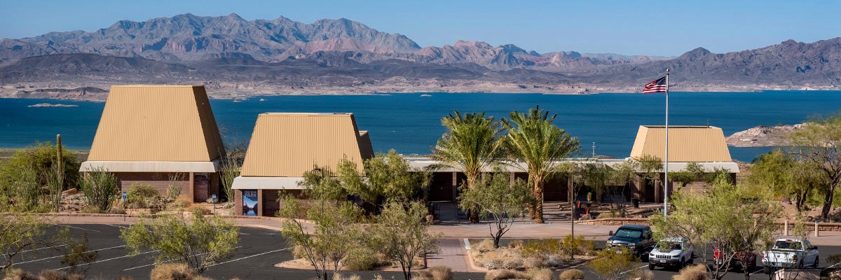 Visitor Center buildings and parking lot with body of water and mountains in background