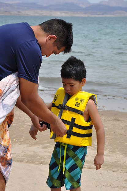 Henry Villafana puts a lifejacket on his son, Nicholas, 5, before he goes swimming at Lake Mead. The lifejacket was borrowed from the Lifejacket Loaner Station at Boulder Beach.