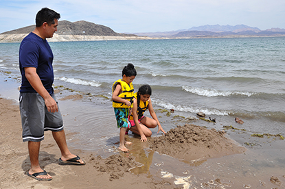 Henry Villafana watches is daughter, Cassandra, 11, and son, Nicholas, 5, play near the water at Lake Mead. The are wearing lifejackets from the Lifejacket Loaner Station.