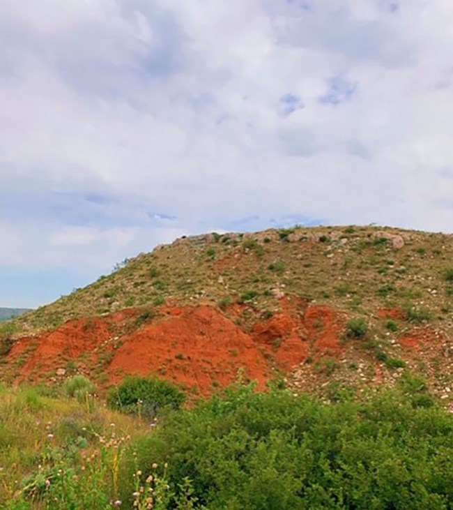 Permian Redbeds with green grasses and plants. The skies are blue.