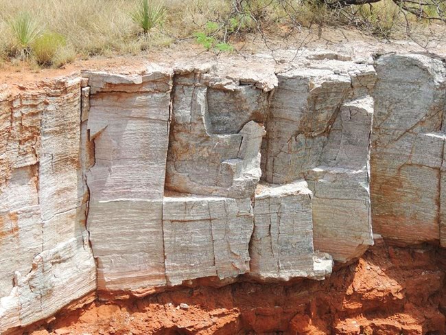 Gypsum near Plum Creek with Permian red beds below and grass growing on top