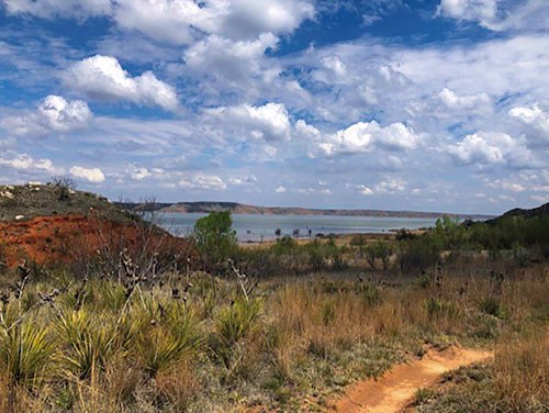 Harbor Bay Trail with view of Lake Meredith on a sunny day.  The trail is reddish-orange layered with Permian dirt.