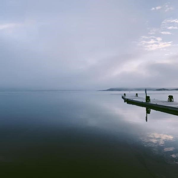 Fritch Fortress boat dock on a foggy morning. The lake is a misty blue and very calm.