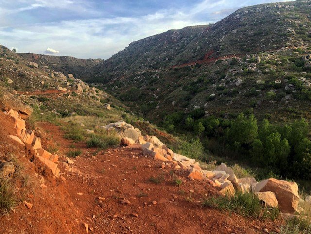 Fritch Fortress Trail in a valley with green foliage on a sunny day with blue skies.