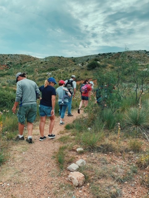 Several visitors hiking up the Alibates Trail on a cloudy day.  The visitors all have on hiking attire.