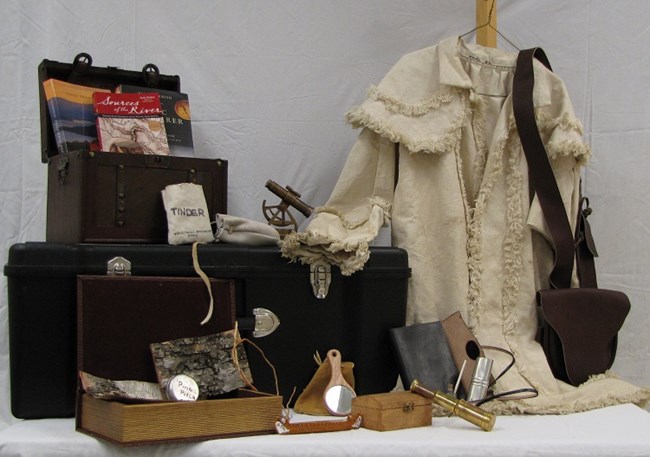 Trunk contents shown, including clothes, a satchel, sextant, journal, reference books, a mirror, a pouch labeled tinder, and other smaller items.