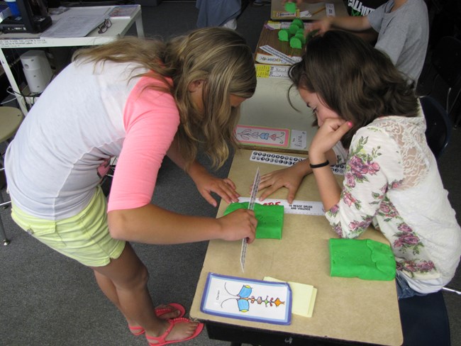 Two students create scale models of planets using play dough