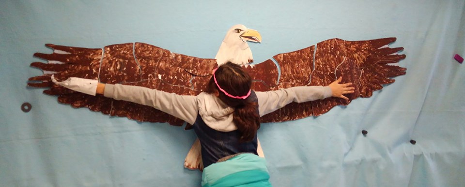 Girl measures her wingspan against that of a life-size bald eagle puzzle