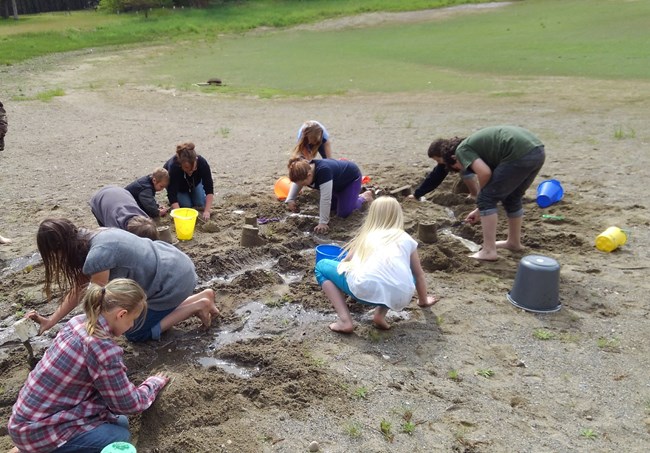 Students build structures on a sandy beach for an Ice Age floods model.