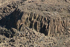 A large mountainside with hexagonal columns of brown-grey basalt rising vertically on the face.