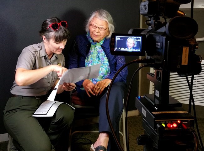 A park ranger works with a woman to record oral history.