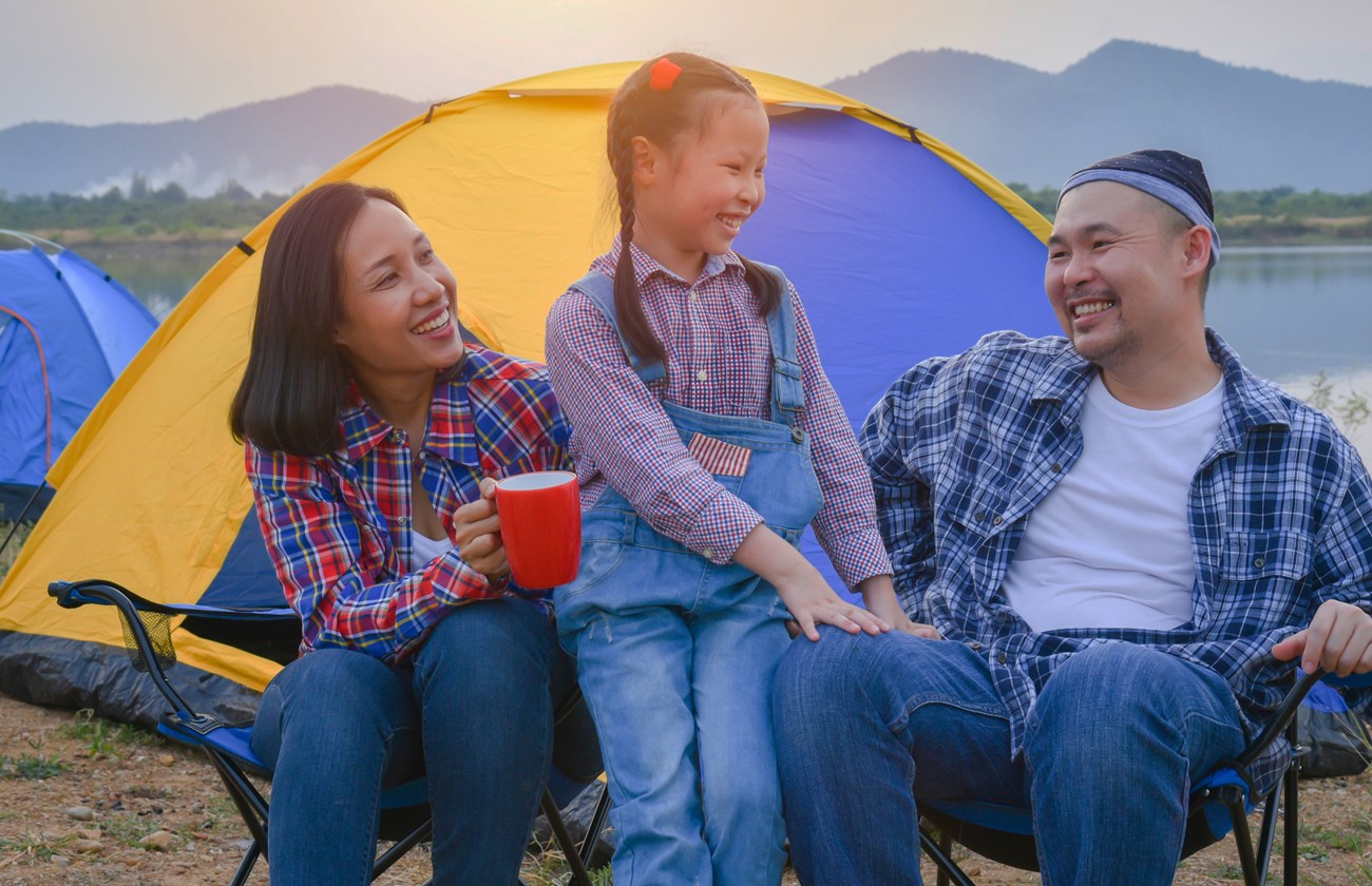 A family group sitting by their tents laughing.