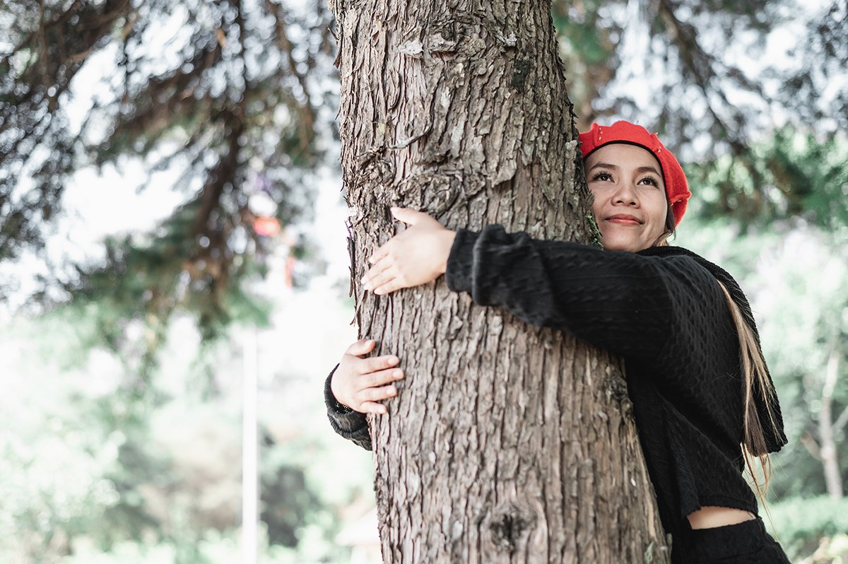 A young woman hugging a tree.