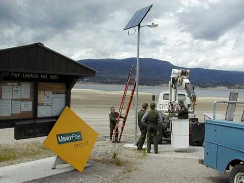 Maintenance installing a solar powered light at a boat dock.