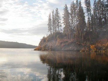 Cove along the shores of Lake Roosevelt. Autumn foliage surround the cove with mist rising from the water.