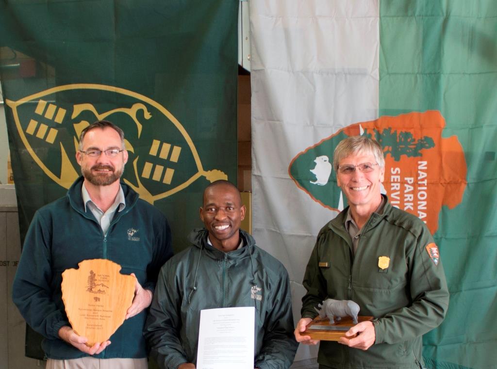 Representatives from South Africa and the National Park Service standing in front of the Ezemvelo KwaZulu-Natal and National Park Service flags
