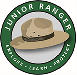 A ranger flat hat with a green circular banner that says Junior Ranger and Explore, Learn, protect.