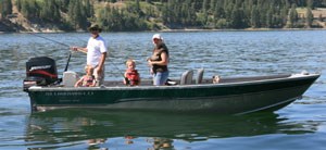 Two adults and two young children on boat on the water fishing.