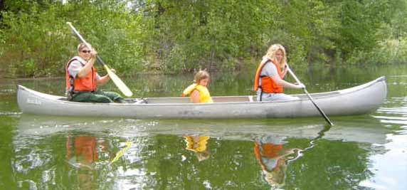 Ranger leading a guided-canoe trip. A ranger with two visitors sitting in a canoe paddling on the water. Ranger leading a guided-canoe trip. A ranger with two visitors sitting in a canoe paddling on the water.