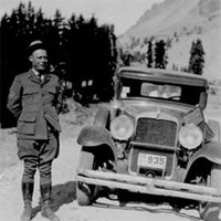 Black and white photo of man in a uniform next to a vehicle circal 1930.