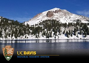 A snow-covered mountain above a blue lake with an arrowhead logo at bottom and another logo that reads "UC Davis Natural Reserve System"