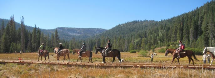 Horseback riders cross a new boardwalk that permits natural water flow in the restored Drakesbad Meadow. Horseback riders cross a new boardwalk that permits natural water flow in the restored Drakesbad Meadow.