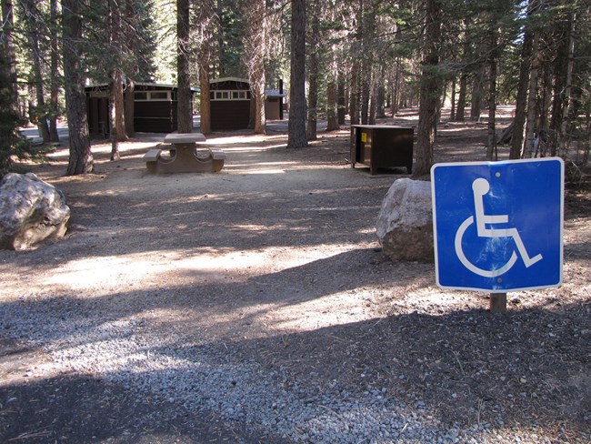 An accessible campsite and bathrooms with a wheelchair symbol sign nearby