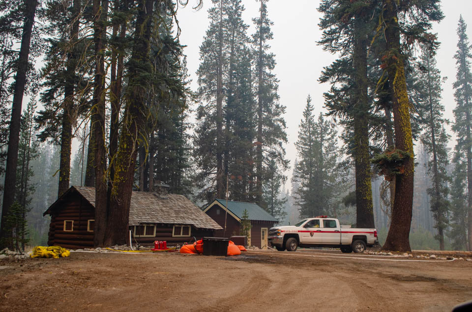 Summit Lake Ranger Station during Dixie Fire A white fire truck and structure protection equipment in front of two single-story, wooden buildings amid conifer trees.