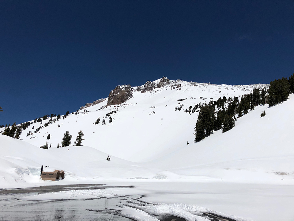 Parking area lined by snow and backed by a large snow-covered mountain