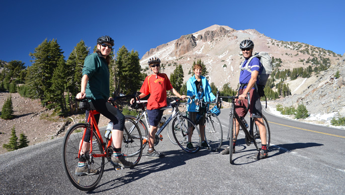 Family on poses for a picture on their bikes in front of Lassen Peak.