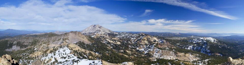 A panoramic photo of a volcanic landscape dotted with snow.