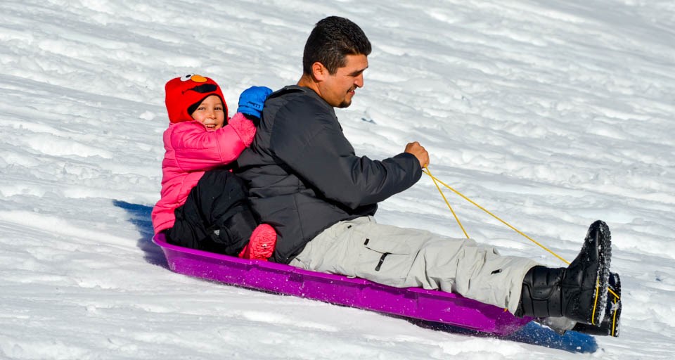 A young girl and a man ride in a sled.